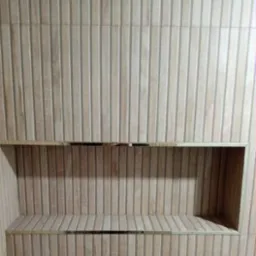 Wykończona wnęka w ścianie łazienki, obłożona płytkami imitującymi drewno z metalowymi listwami dekoracyjnymi. Pionowy układ płytek.