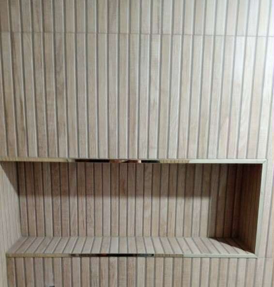 Wykończona wnęka w ścianie łazienki, obłożona płytkami imitującymi drewno z metalowymi listwami dekoracyjnymi. Pionowy układ płytek.