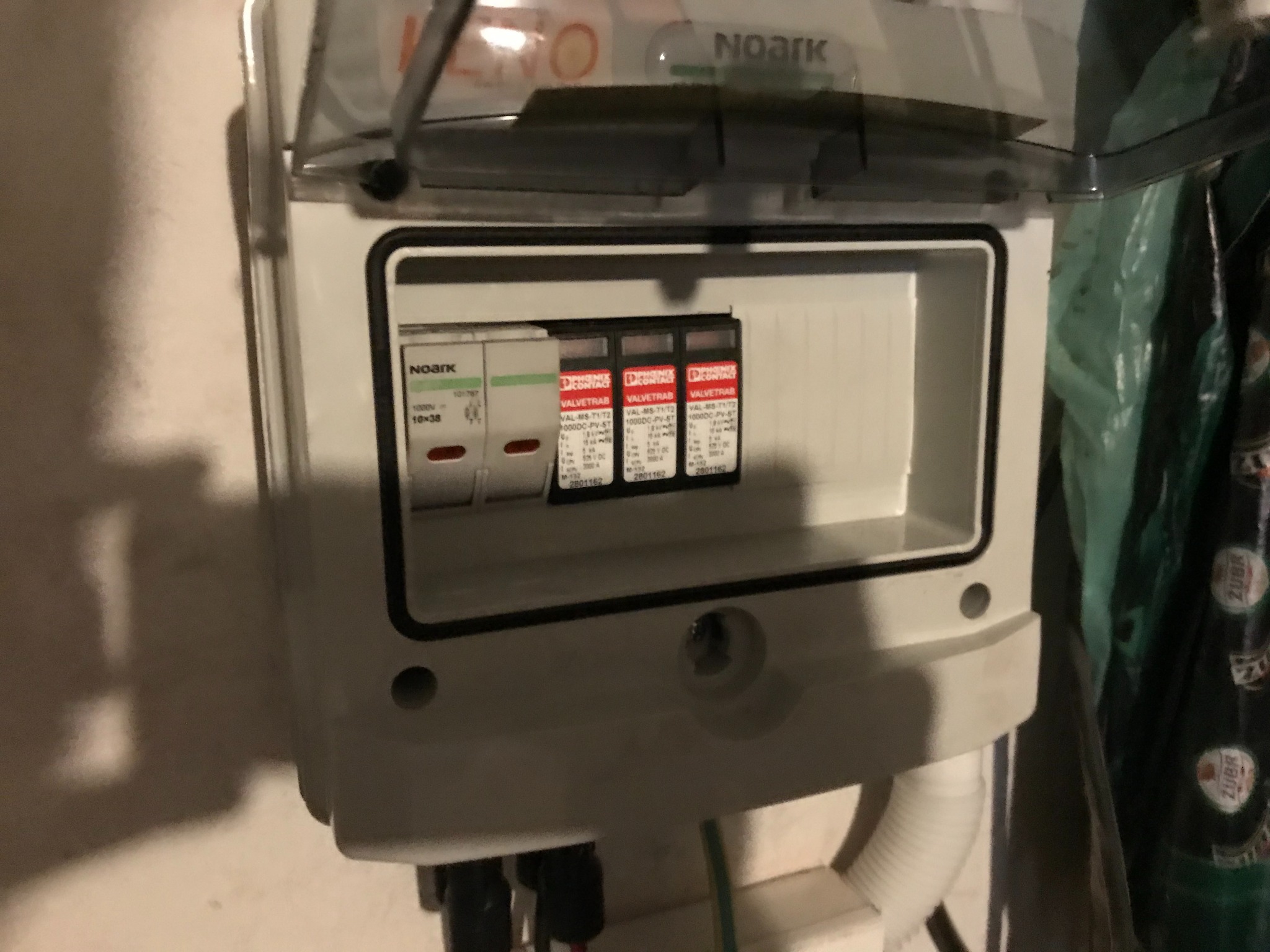 Otwarta skrzynka z zabezpieczeniami przepięciowymi Noark i Phoenix Contact VALVETRAB, zamontowana na ścianie. Widoczne przewody i elementy instalacji.