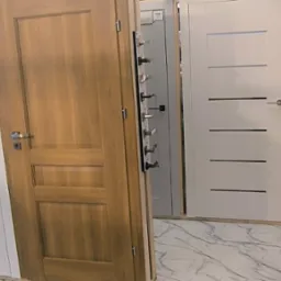 Ekspozycja różnorodnych drzwi wewnętrznych: białe z poziomymi frezami, drewniane w ciepłym odcieniu dębu, oraz nowoczesne czarne z elementami z jasnego drewna.