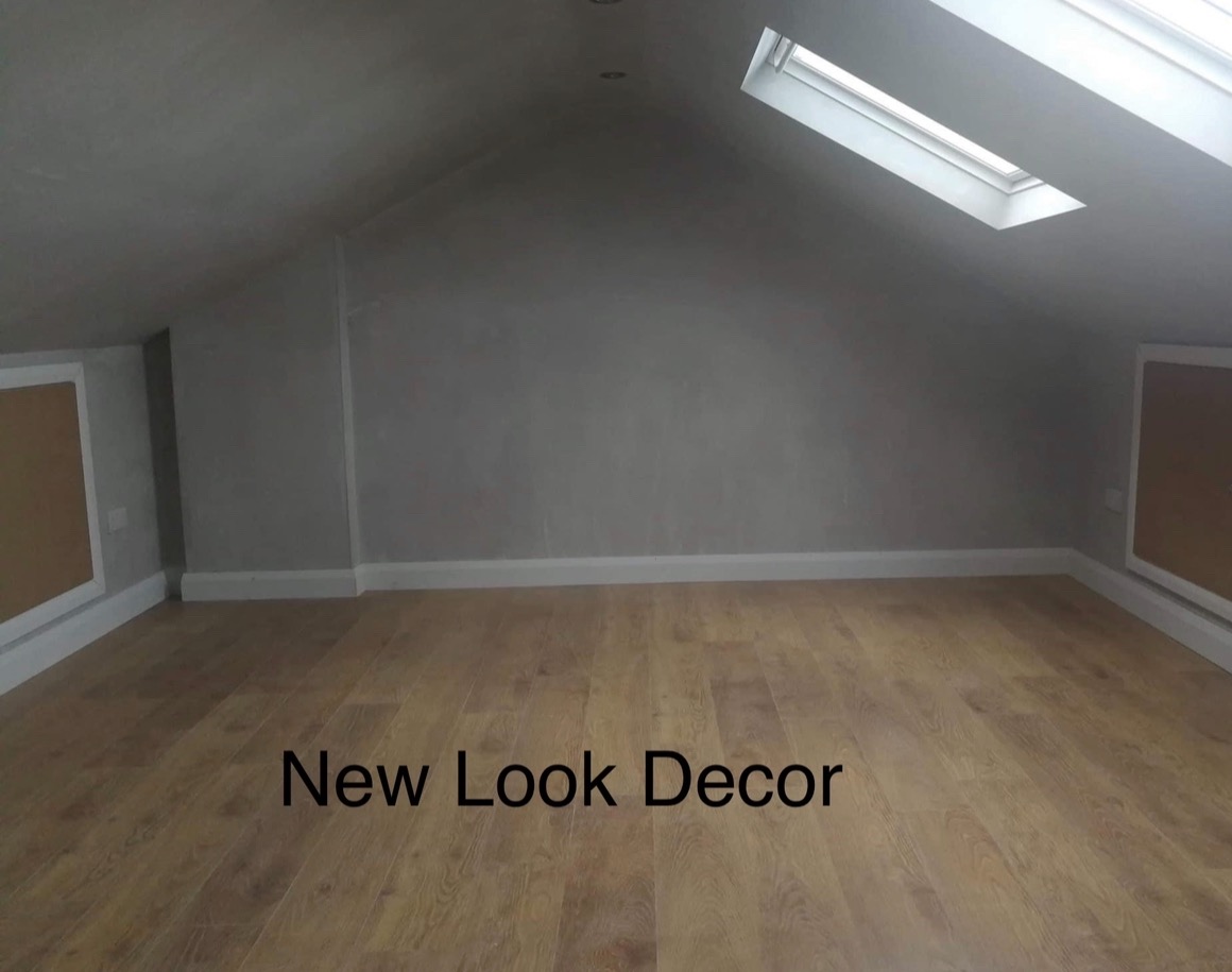 Poddasze po remoncie: gładkie, szare ściany, jasna podłoga z paneli, białe listwy przypodłogowe i okno dachowe w skosie. Nowoczesne wykończenie wnętrza.