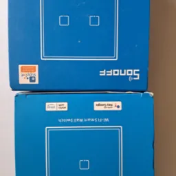 Dwa opakowania niebieskich, inteligentnych włączników ściennych Wi-Fi Sonoff. Opakowania wskazują na kompatybilność z Alexa i Google Home.