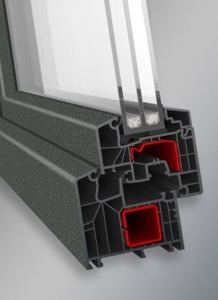 Przekrój okna PCV Aluplast z widocznymi komorami powietrznymi, uszczelkami i szybami zespolonymi. Detal konstrukcyjny, szary profil ramy okiennej, oświetlenie studyjne.