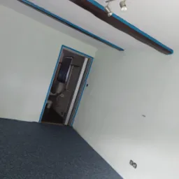 Białe ściany z drewnianymi belkami i niebieską taśmą malarską, widok na łazienkę, szara wykładzina. Przygotowanie do malowania.