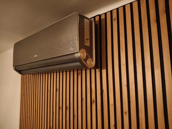 Klimatyzator AUX w kolorze grafitowym, zamontowany na ścianie z drewnianych paneli w Kutnie. Nowoczesny design i eleganckie wykończenie.