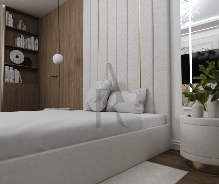 Nowoczesna sypialnia z tapicerowanym panelem ściennym w beżowej tonacji, minimalistyczną lampą wiszącą i drewnianą zabudową. Widoczne detale: stolik nocny i dekoracje.