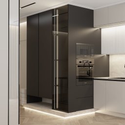 Meble Moras Piotr - Minimalistyczna kuchnia z czarnymi szafkami i oświetleniem LED, widok z boku, parkiet w jodełkę, elementy zabudowy kuchennej z piekarnikiem i mikrofalówką.