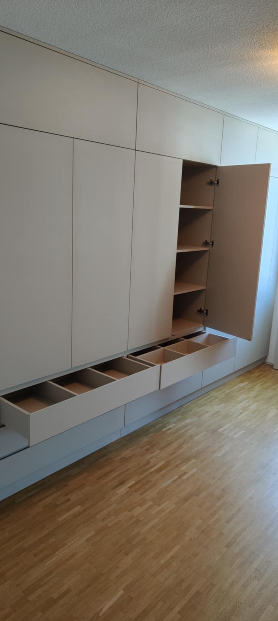 Jasna szafa wnękowa z otwartymi szufladami i półkami w Radomsku. Minimalistyczny design, drewniana podłoga, subtelne oświetlenie.