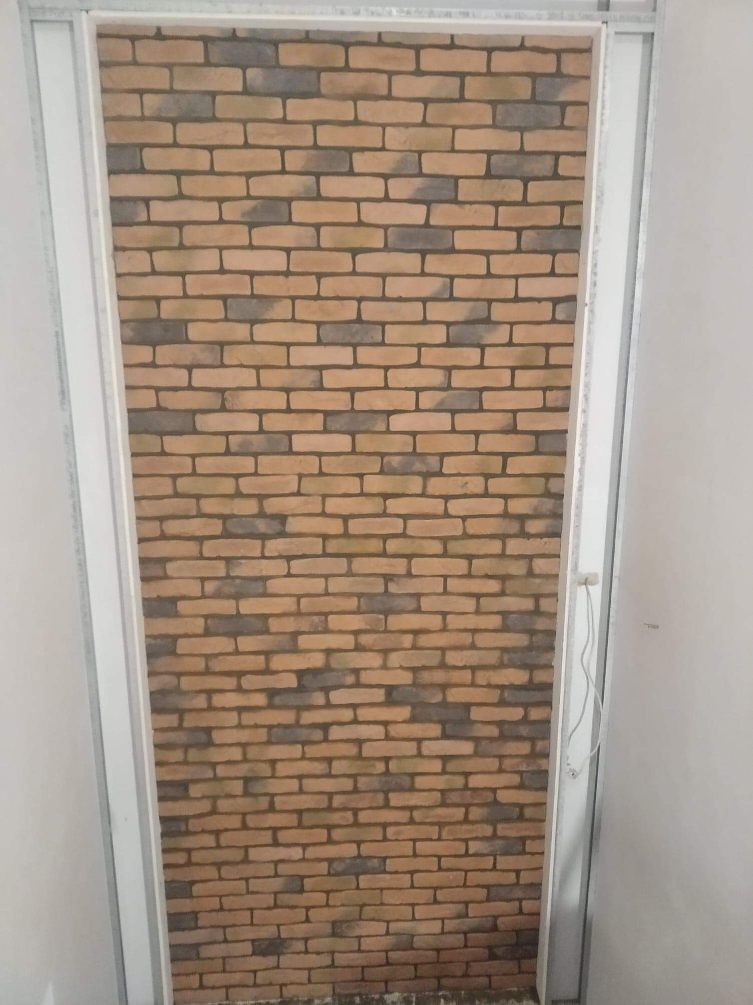 Ściana z cegieł dekoracyjnych w metalowej ramie, imitująca starą cegłę. Widoczne detale faktury i koloru, tworzące efekt rustykalny.