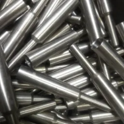 Stalowe, precyzyjnie wytoczone elementy z otworem, ułożone chaotycznie, ukazujące metaliczny połysk i dokładność wykonania.