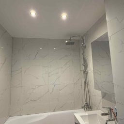 Nurii S.C. - Wykończona, jasna łazienka z wanną, umywalką i marmurowymi płytkami. Widoczne oświetlenie punktowe i chromowana armatura. Minimalistyczny design.