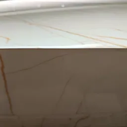 Detal marmurowej okładziny ściennej z subtelnym, złotym żyłkowaniem pod jasnym oświetleniem, ukazując precyzję wykonania i estetykę wykończenia.