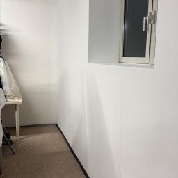 Wykończenia ,szpachlowanie ,malowanie ,płytki - Wnętrze po odświeżeniu: białe ściany z oknem w grubym murze, brązowa wykładzina, czarna listwa przypodłogowa. Minimalistyczny wystrój, neutralna kolorystyka.