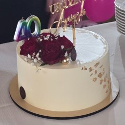 RS SPÓŁKA Z OGRANICZONĄ ODPOWIEDZIALNOŚCIĄ - Tort urodzinowy z dekoracją z czerwonych róż, świeczką w kształcie liczby 40 i topperem '40 Urodziny Anny', różowe balony w tle.