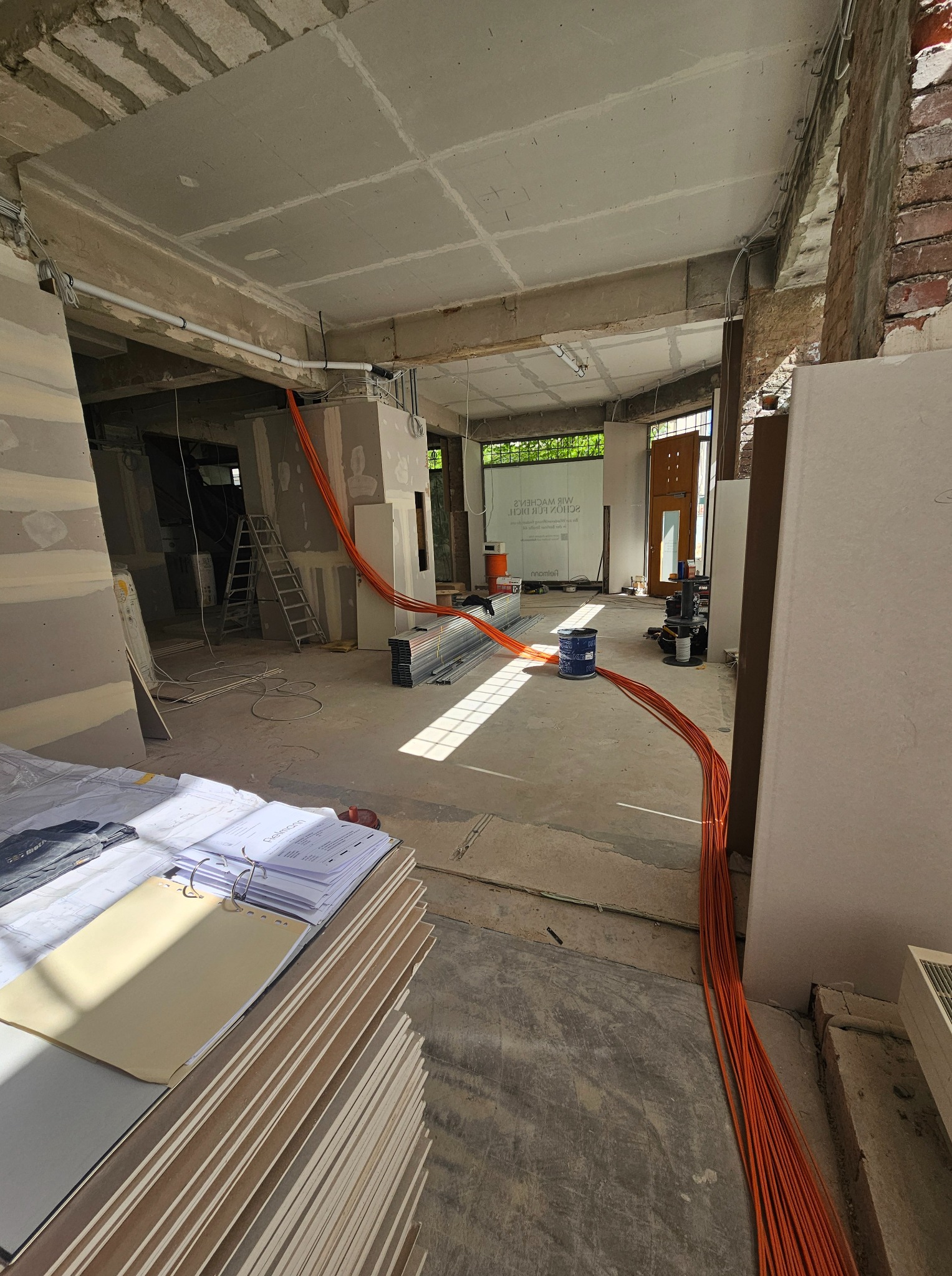 Instalacja elektryczna w trakcie remontu w Jelcz-Laskowice. Widoczne kable, płyty gipsowe i plany. Etap prac przed wykończeniem.