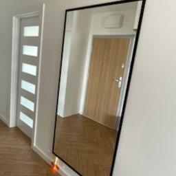 GoldenGlass Filip Staniszewski - lustro w czarnej ramce w przedpokoju, robi robotę