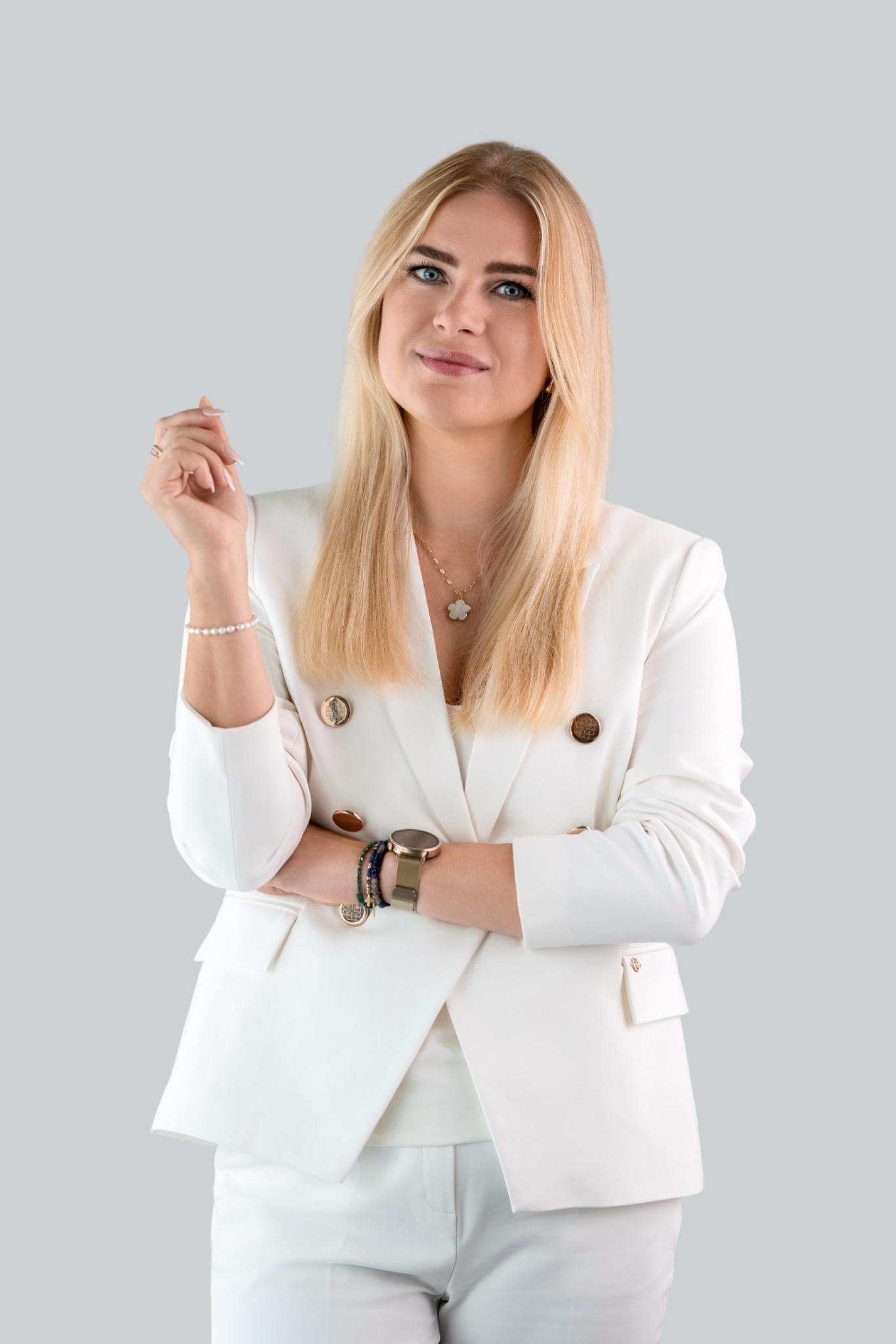 Portret blondynki w białym garniturze na neutralnym tle. Uśmiech, biżuteria, profesjonalny wizerunek. Idealne zdjęcie profilowe doradcy.