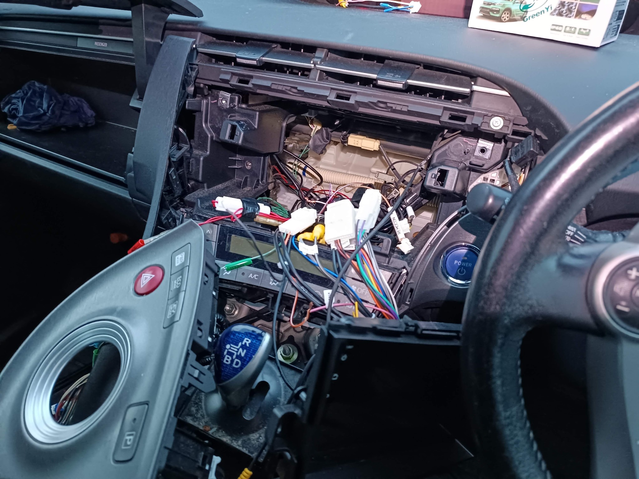 Rozmontowany kokpit samochodu z widocznymi przewodami i elementami deski rozdzielczej. Widoczne elementy sterowania i skrzynia biegów.