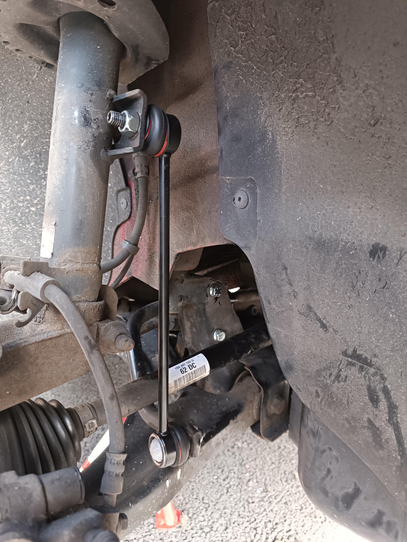 Element zawieszenia samochodu po wymianie łącznika stabilizatora. Widoczne nowe śruby mocujące i gumowe elementy. Detal z warsztatu samochodowego.