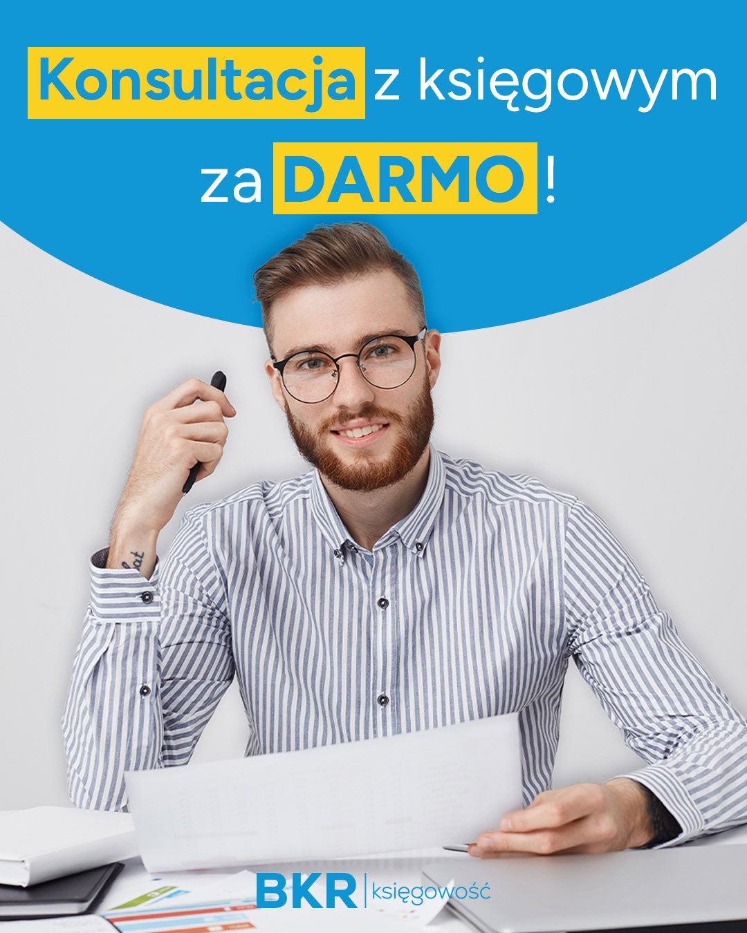 Uśmiechnięty mężczyzna w okularach, konsultacja księgowa za darmo, biuro rachunkowe BKR. Mężczyzna trzyma dokumenty i długopis, siedzi za biurkiem.
