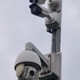 Zestaw kamer Hikvision na słupie w Ząbkach. Dwie kamery tubowe i jedna obrotowa, szare tło nieba. Widoczne elementy montażowe i przewody.