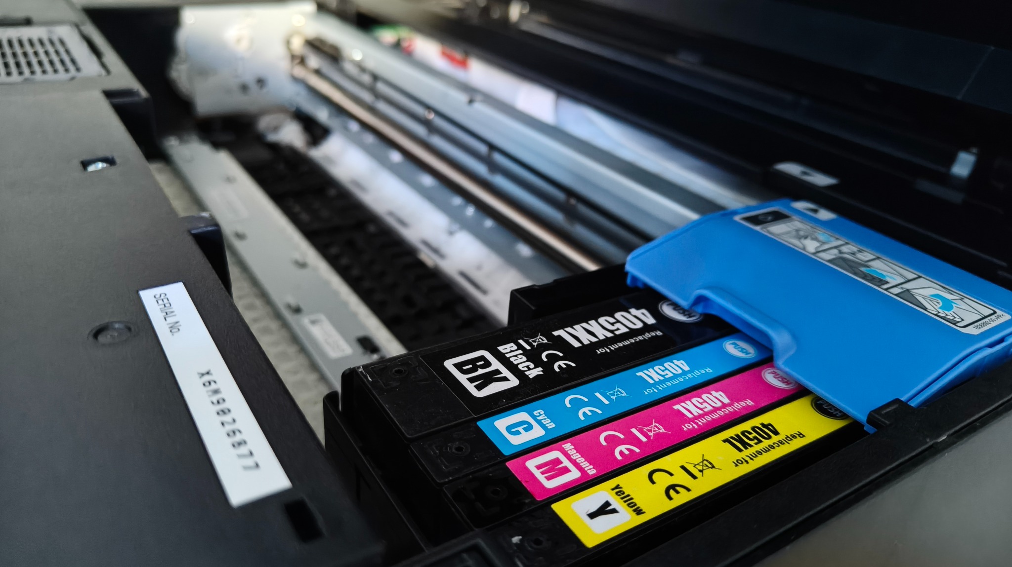 Wnętrze drukarki z wkładami 405XXL: czarnym, cyjan, magenta i żółtym. Widoczny numer seryjny X6M9026877. Wkłady ułożone w kasecie, gotowe do wymiany.