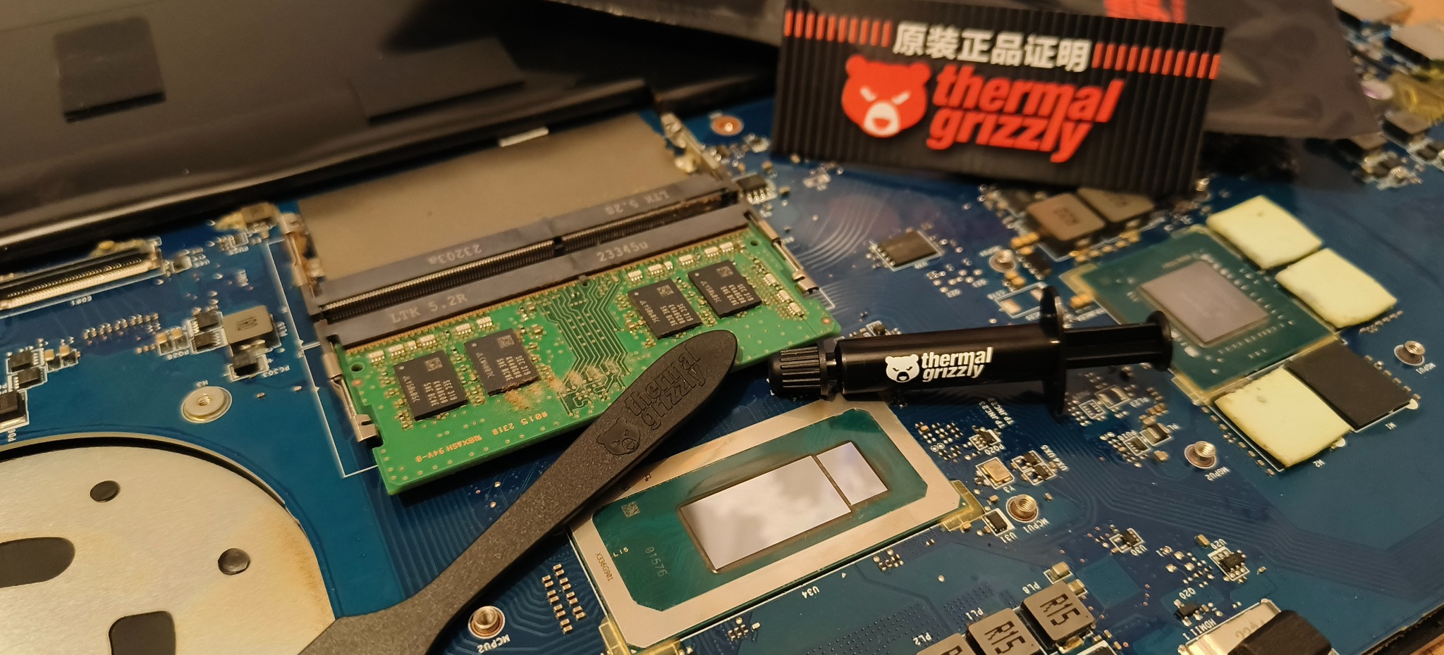 Otwarty laptop z widoczną płytą główną, procesorem, pamięcią RAM i pastą termoprzewodzącą Thermal Grizzly. Detaliczna naprawa sprzętu komputerowego.