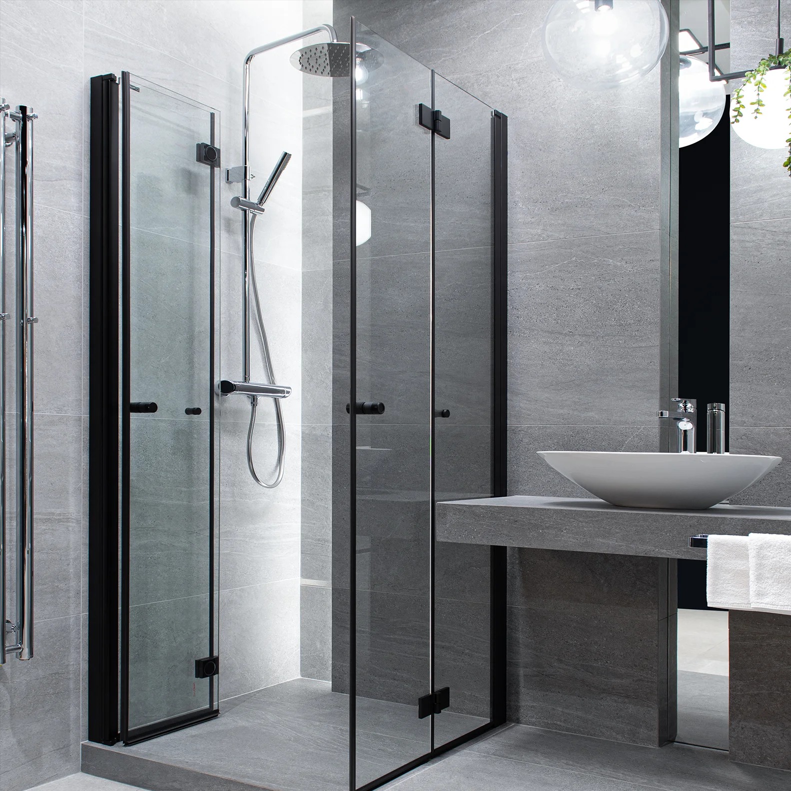 Nowoczesna łazienka z szarą armaturą: kabina prysznicowa z czarnymi ramami, umywalka nablatowa i grzejnik drabinkowy. Minimalistyczny design, płytki imitujące kamień.