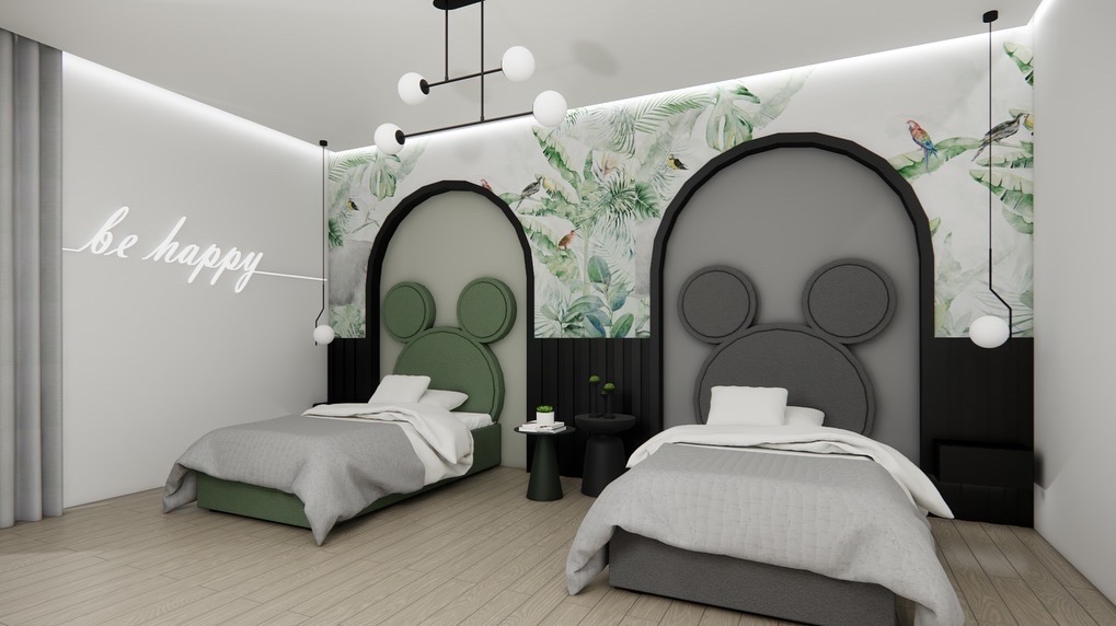 Pokój dziecięcy z dwoma łóżkami w stylu Myszki Miki, zielonym i szarym, na tle tapety w liście i napis 'be happy' na ścianie. Nowoczesne lampy wiszące.