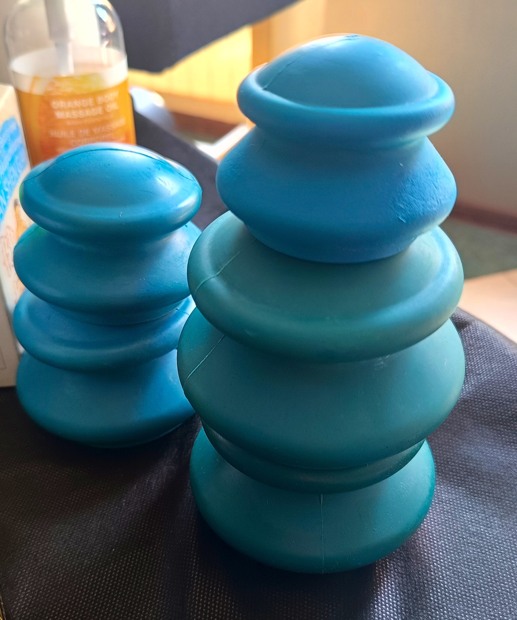 Dwie wieże z niebieskich, silikonowych baniek do masażu próżniowego, obok butelka olejku do masażu. Sprzęt do masażu w salonie kosmetycznym lub gabinecie fizjoterapii.