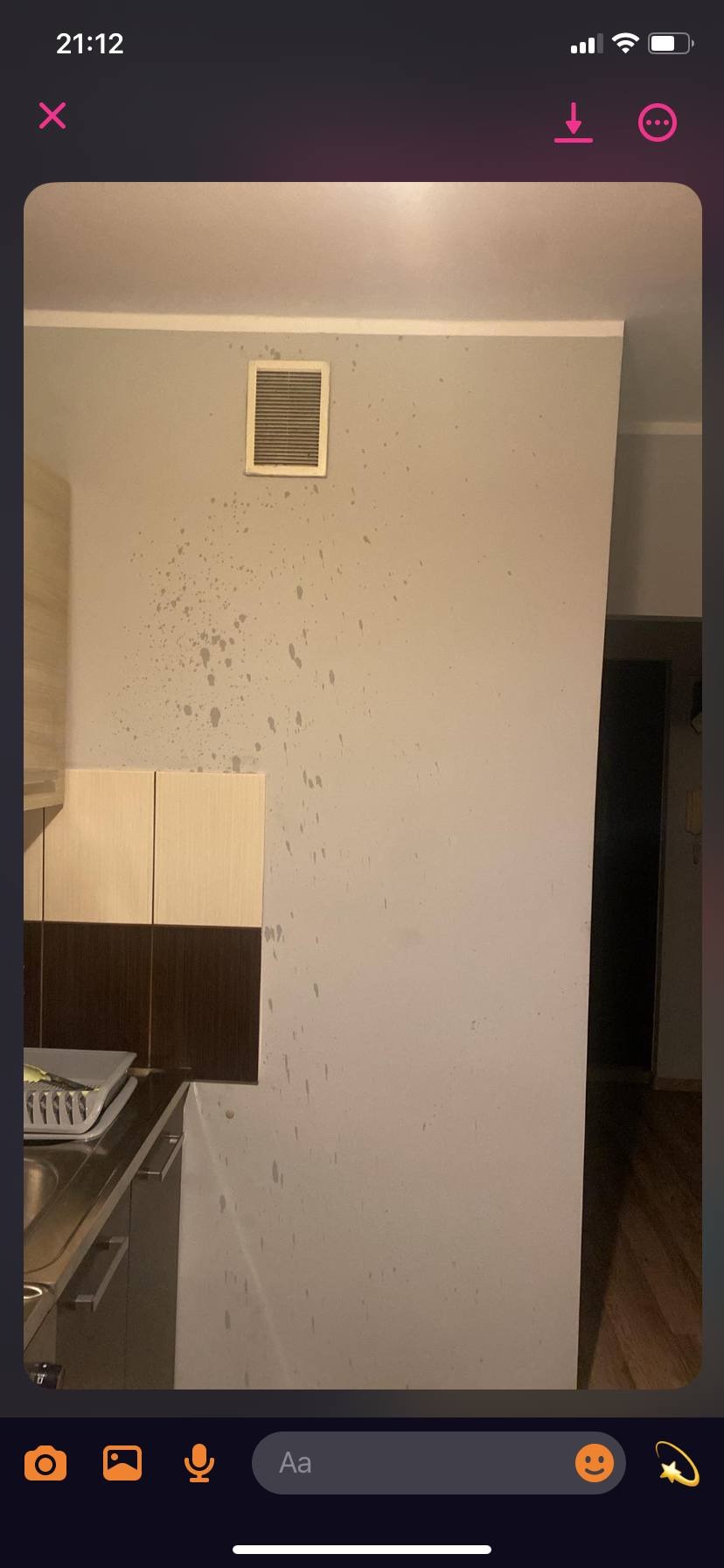 Ściana w kuchni z widocznymi zabrudzeniami przed malowaniem. Kratka wentylacyjna i fragment szafek kuchennych. Widoczne plamy i zacieki na ścianie.