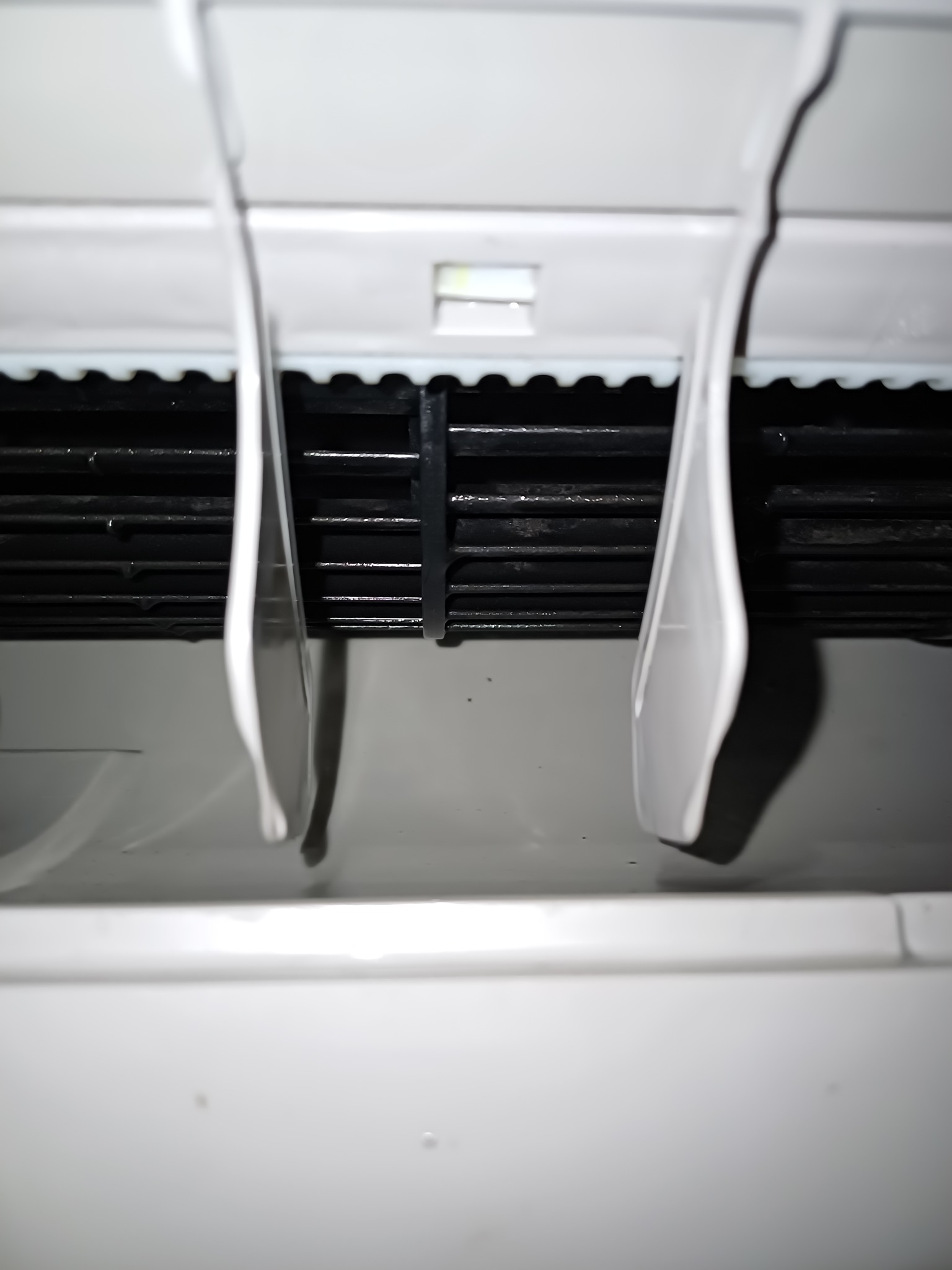 Detal klimatyzatora z widoczną kratką wlotową powietrza i regulowanymi żaluzjami, ukazujący czystość i sprawność urządzenia.