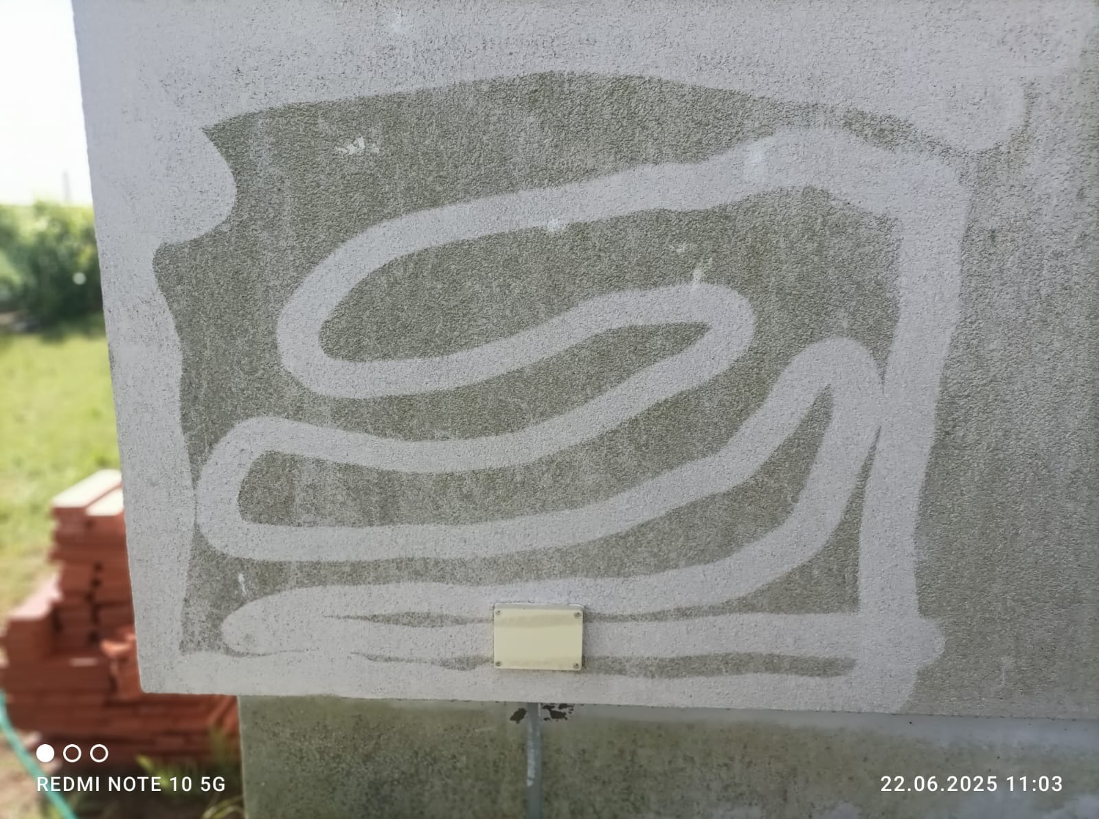 Fragment elewacji z widocznym efektem czyszczenia, ukazującym kontrast między umytą a zabrudzoną powierzchnią. Widoczny wzór czyszczenia i niewielki element instalacji.