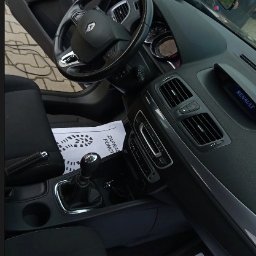 AI Detailing - Wnętrze Renault Megane po czyszczeniu: czarna tapicerka, kierownica z logo, kartka z napisem 'Zapraszamy ponownie'. Widok z perspektywy kierowcy.