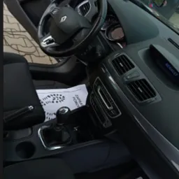 Wnętrze Renault Megane po czyszczeniu: czarna tapicerka, kierownica z logo, kartka z napisem 'Zapraszamy ponownie'. Widok z perspektywy kierowcy.