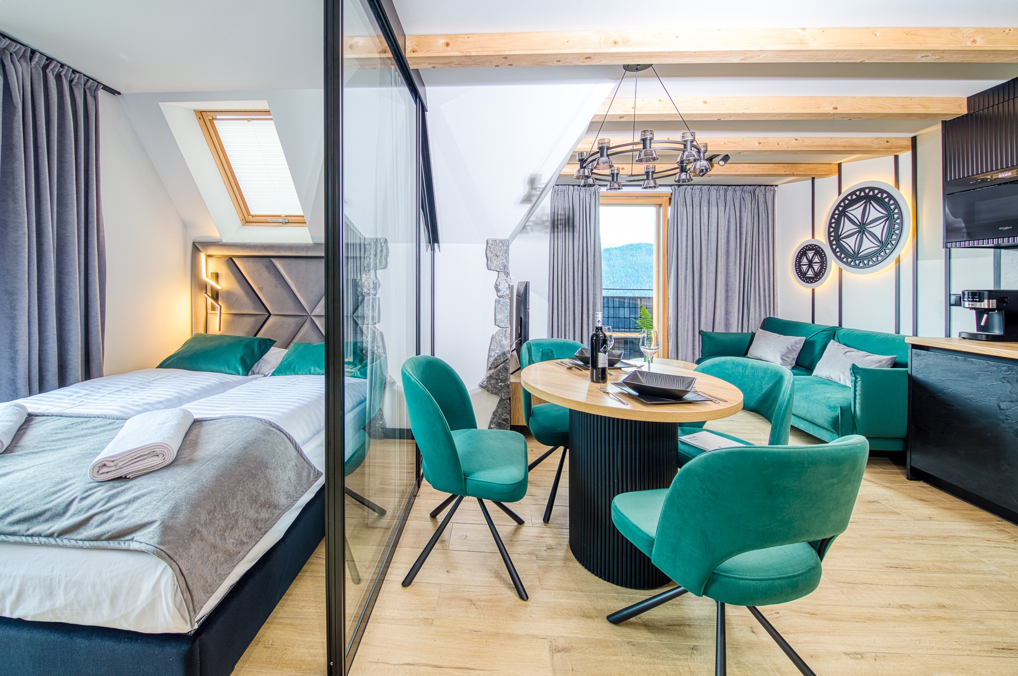 Jasne wnętrze apartamentu w stylu loft: sypialnia z łóżkiem, przeszklona ściana, okrągły stół z krzesłami i salon z sofą w odcieniach zieleni. Widok na góry.