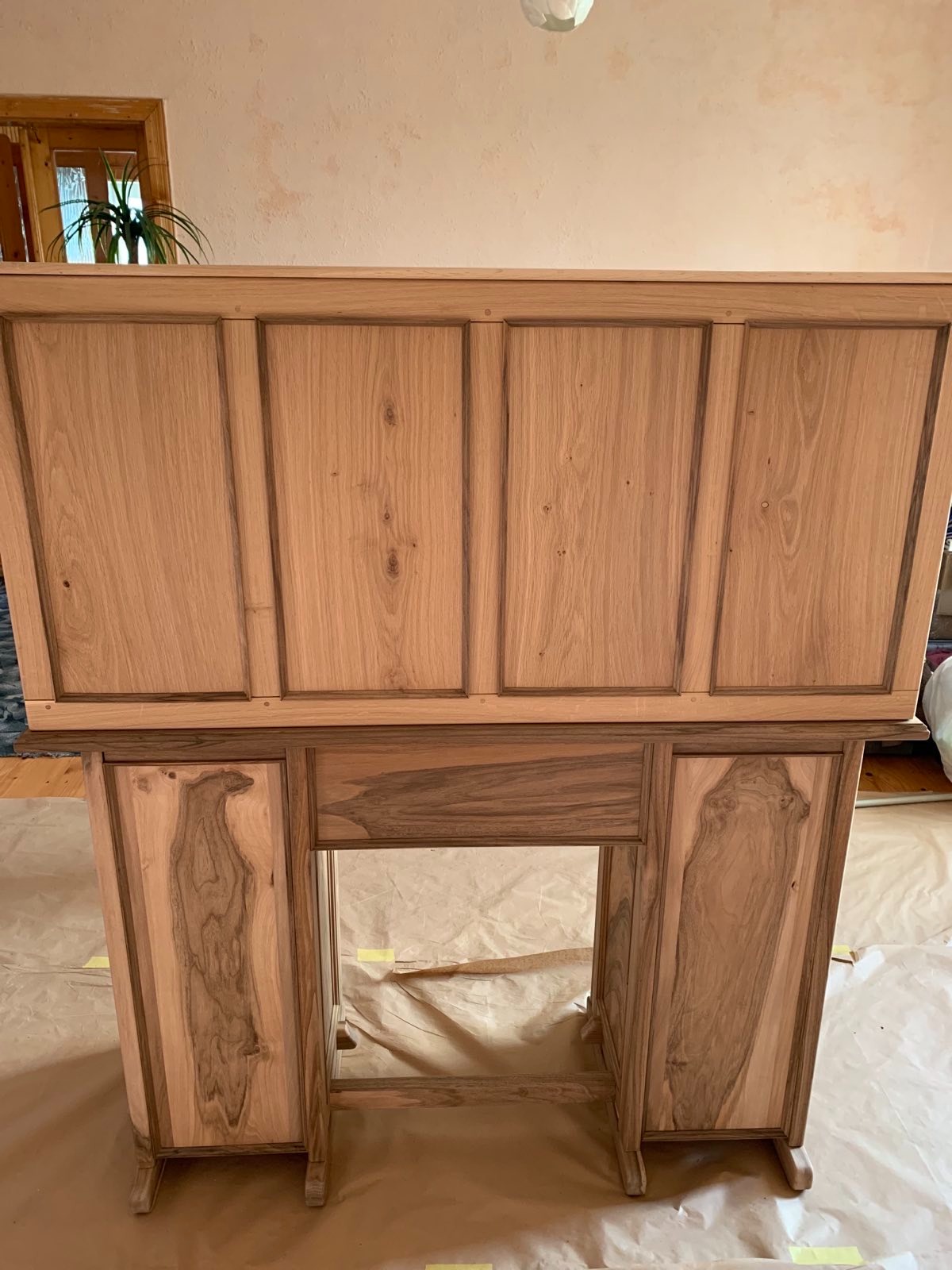 Odrestaurowane biurko z jasnego drewna z widocznymi panelami i charakterystycznym usłojeniem, na papierze ochronnym, w domowym wnętrzu.