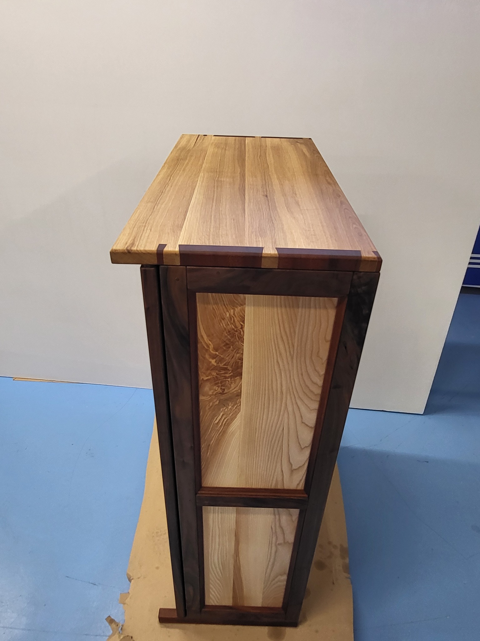 Drewniana komoda z unikalnym wzorem słojów, wykonana we Wrocławiu. Mebel z ciemną ramą i jasnym wnętrzem, widoczne połączenia stolarskie.