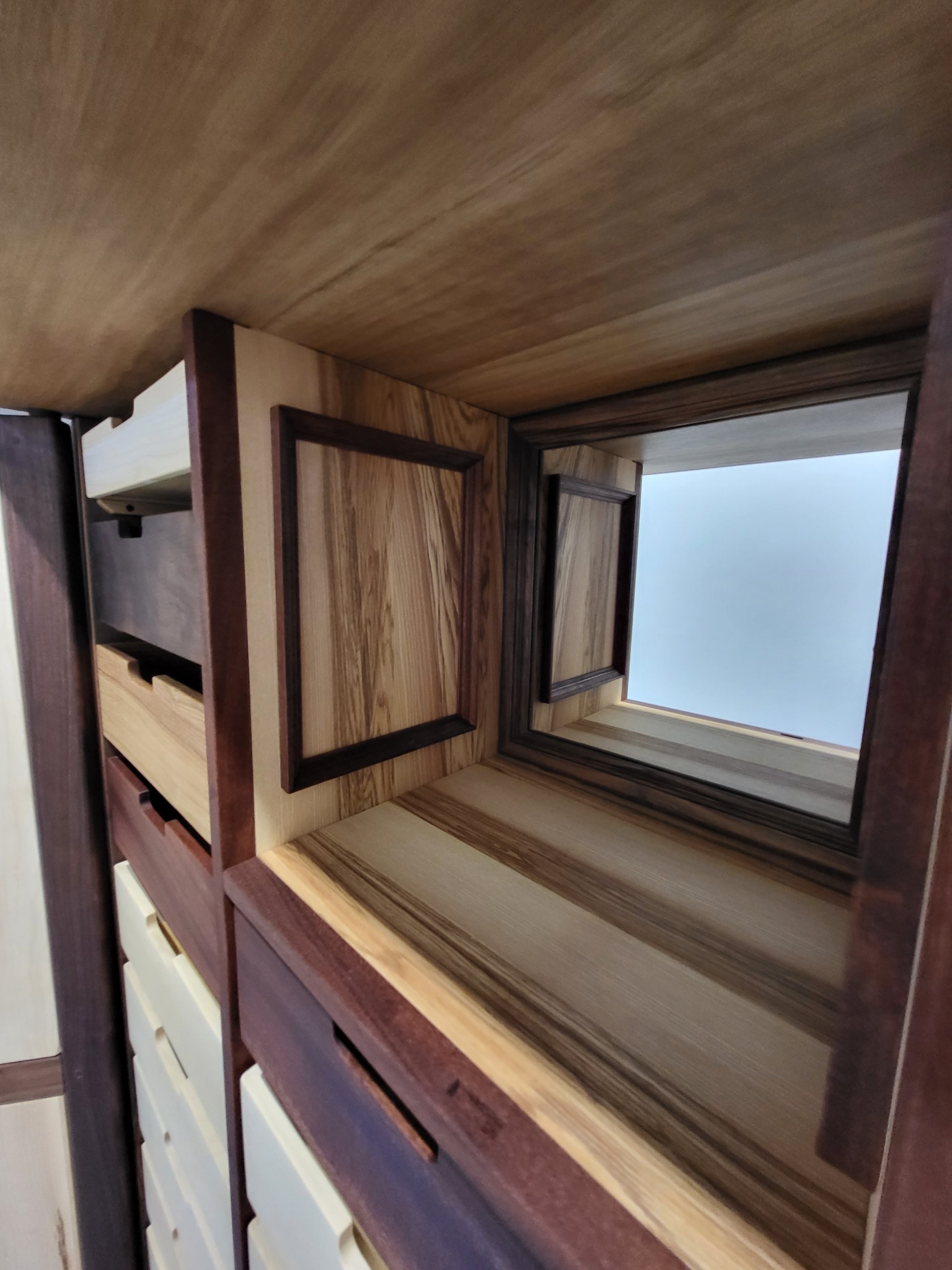 Drewniana zabudowa z szufladami i dekoracyjnymi elementami, wykonana z różnych gatunków drewna. Widok od dołu, z perspektywą na sufit.