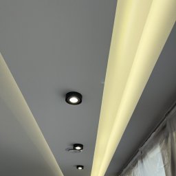 Zabudowy Wnętrz Paweł Wójcik - Sufit z oświetleniem LED wzdłuż krawędzi i punktowymi lampami, świeżo pomalowany, z folią ochronną na oknie. Nowoczesne wykończenie wnętrza.