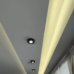 Sufit z oświetleniem LED wzdłuż krawędzi i punktowymi lampami, świeżo pomalowany, z folią ochronną na oknie. Nowoczesne wykończenie wnętrza.