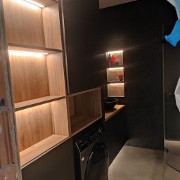 PARLAN Bartłomiej Giefert - Nowoczesna łazienka z szafkami na wymiar z podświetleniem LED, czarnymi ścianami i pralką. Umywalka nablatowa i półki wnękowe dodają elegancji.