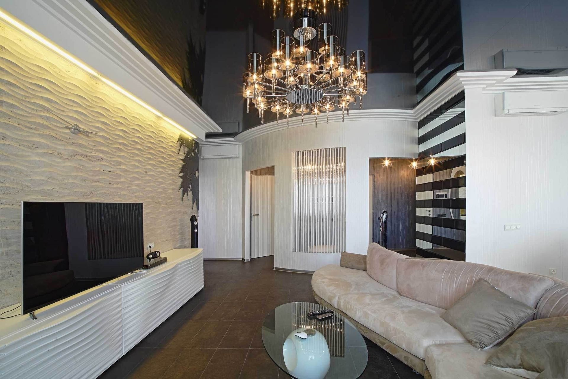 Salon z błyszczącym, czarnym sufitem i dekoracyjnym oświetleniem. Ściana z fakturą, nowoczesne meble i okrągły stolik kawowy.