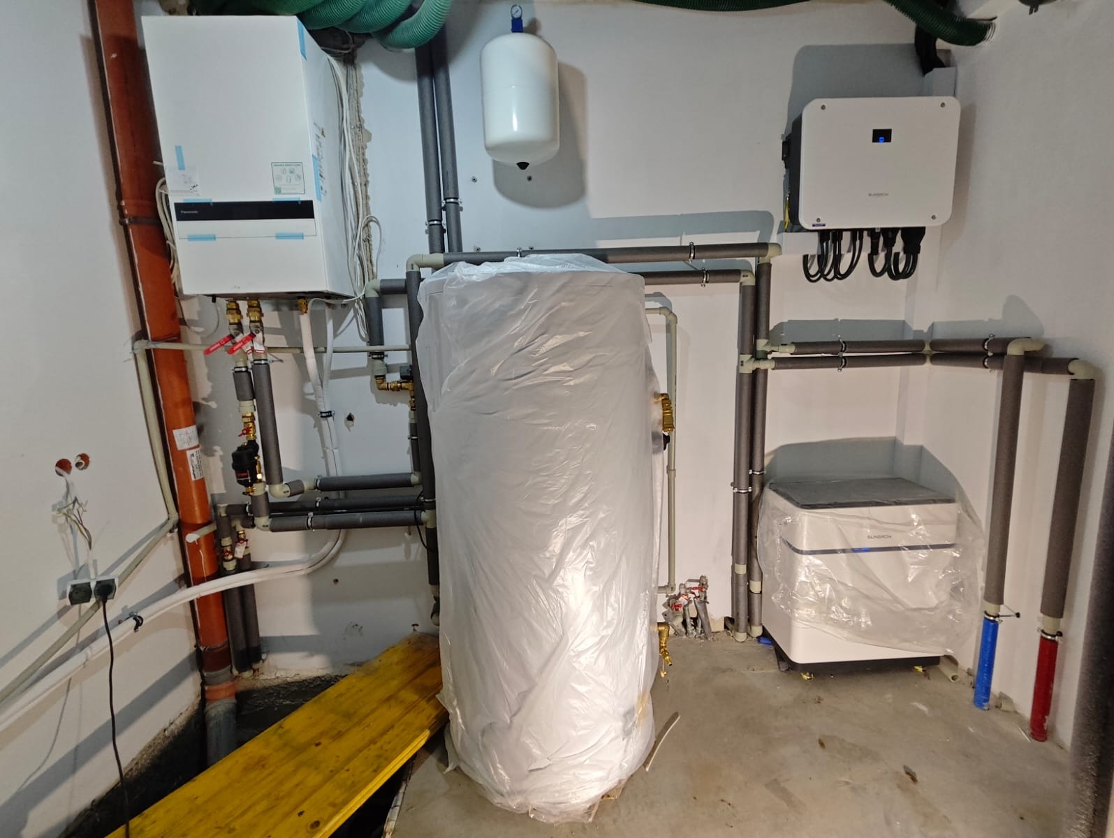 Kompleksowa instalacja w budynku: fotowoltaika, pompa ciepła, wentylacja mechaniczna z odzyskiem ciepła i klimatyzacja. Elementy instalacji częściowo zabezpieczone folią.