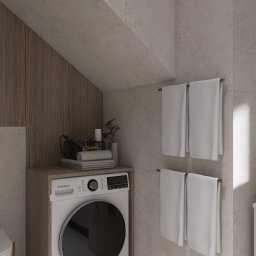 Wiktoria Nowocień NOVO - Projekt łazienki: pralka zabudowana w szafce z drewnianym wykończeniem, ręczniki na wieszaku, beżowe płytki na ścianach i podłodze, skośny sufit.
