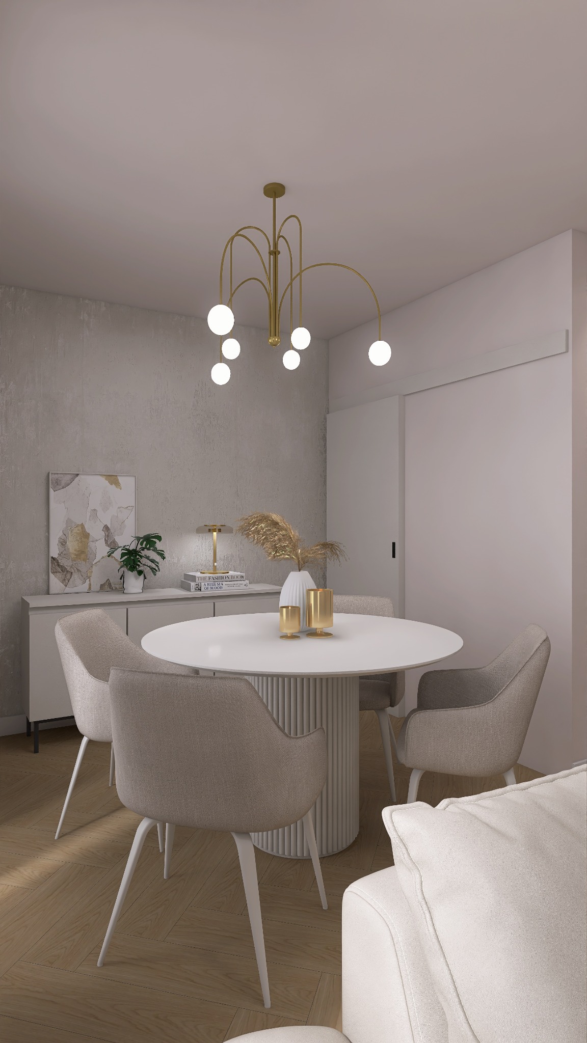 Jasne wnętrze jadalni z okrągłym stołem, krzesłami w odcieniach beżu i złotym, nowoczesnym żyrandolem. Na komodzie dekoracje i obraz w stonowanych barwach.