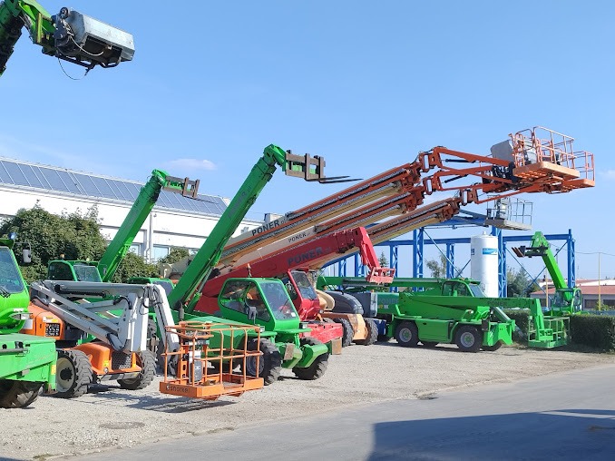 Rząd wielobarwnych ładowarek teleskopowych marki Poner, ustawionych na placu budowy, z podniesionymi ramionami i koszami roboczymi na tle błękitnego nieba.