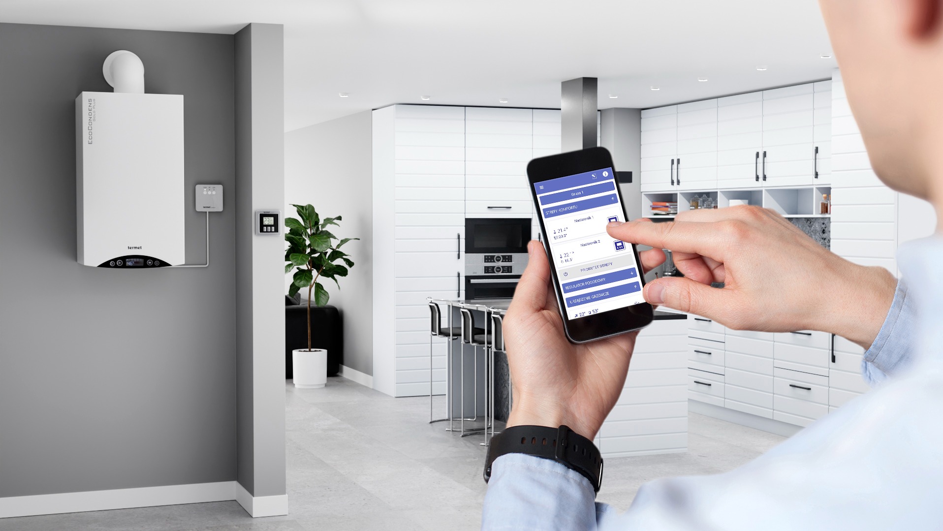 Inteligentny system ogrzewania: Osoba obsługuje aplikację na smartfonie, kontrolując ustawienia kotła gazowego Termet w nowoczesnej kuchni.