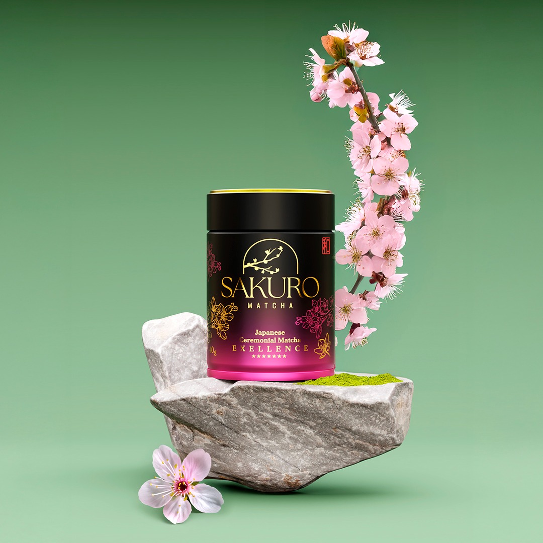 Elegancka puszka Sakuro Matcha na kamiennej podstawie, ozdobiona kwiatem wiśni na tle pistacjowego studia. Produkt japoński, ceremonialna jakość.
