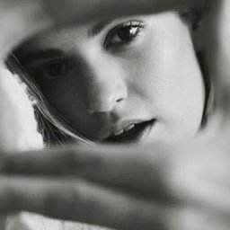ZMATRYCY Paweł Niedźwiedź - Czarno-biały portret kobiety z bliska, z delikatnym uśmiechem, widzianej przez nieostre przeszkody, tworzące unikalną ramę dla twarzy. Oświetlenie podkreśla rysy.